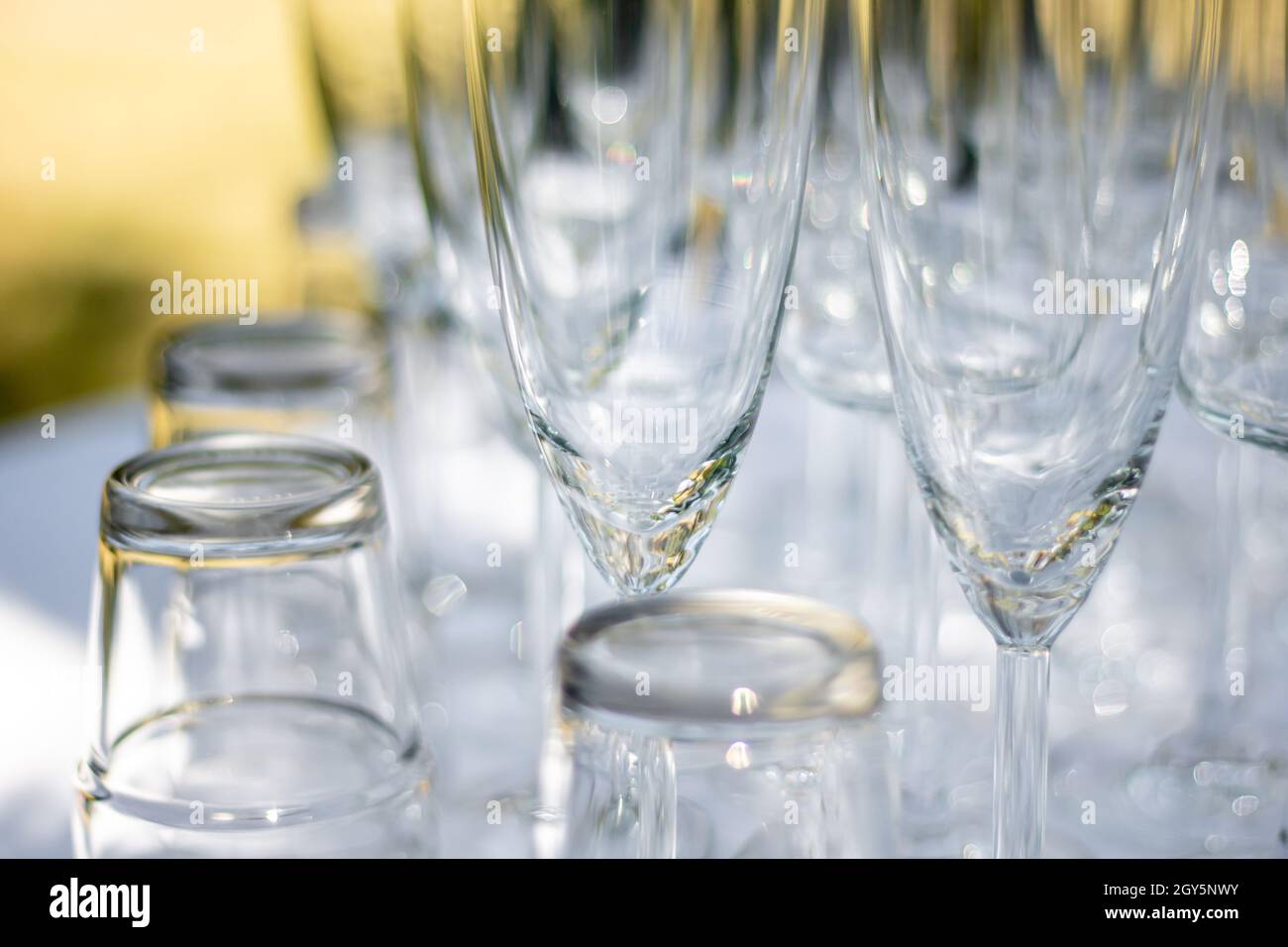 Nahaufnahme von verschiedenen Gläsern, Sektgläsern und Cocktailgläsern auf einem Tisch mit weißer Tischdecke, Fokus auf Sektgläser Stockfoto
