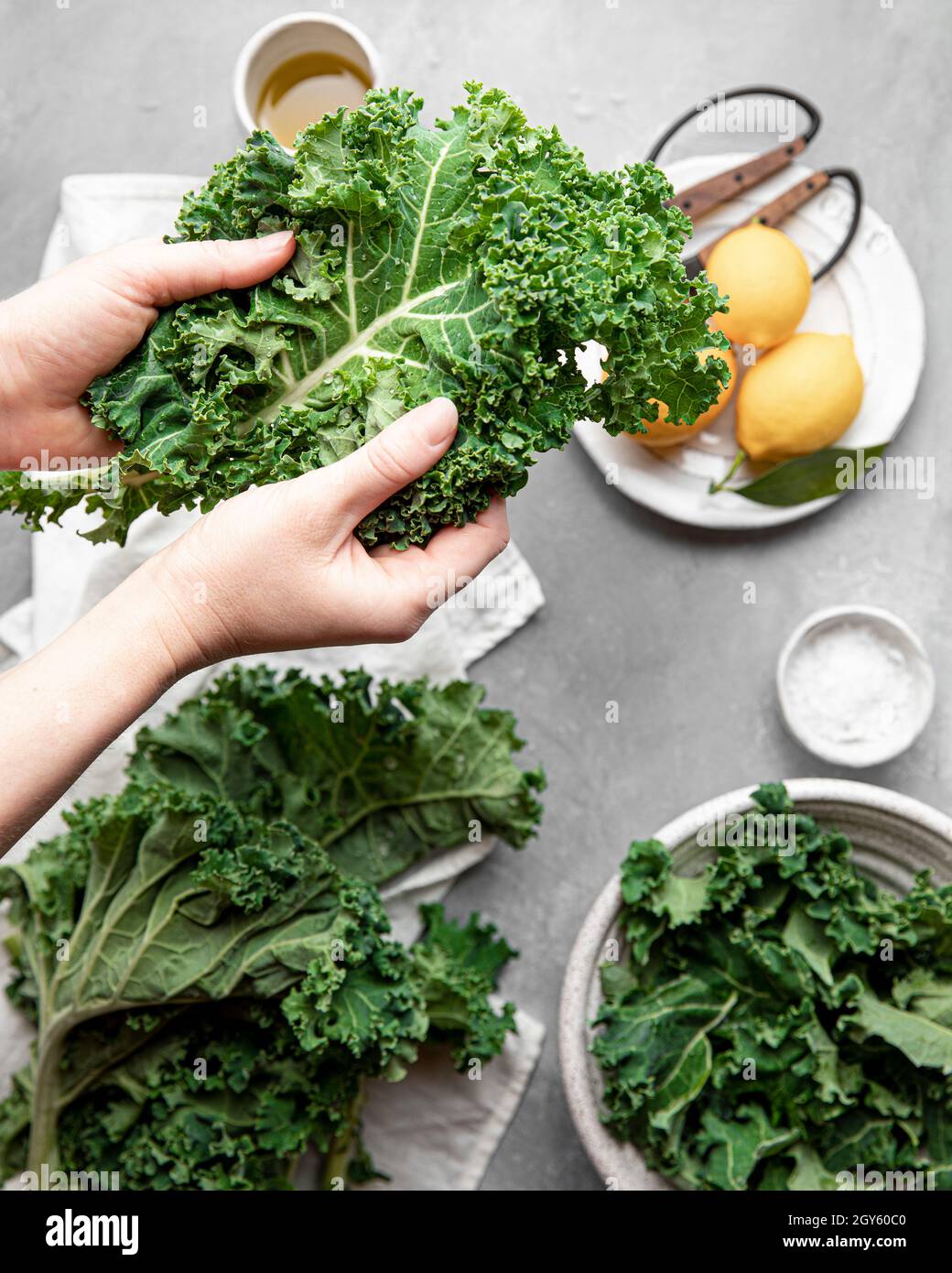 Hände mit einem leuchtend grünen, frisch gewaschenen, lockigen Grünblatt Stockfoto