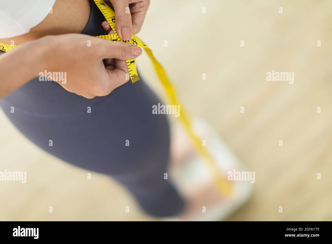 Die junge Frau steht auf einer Waage und misst die Taillengröße Stockfoto