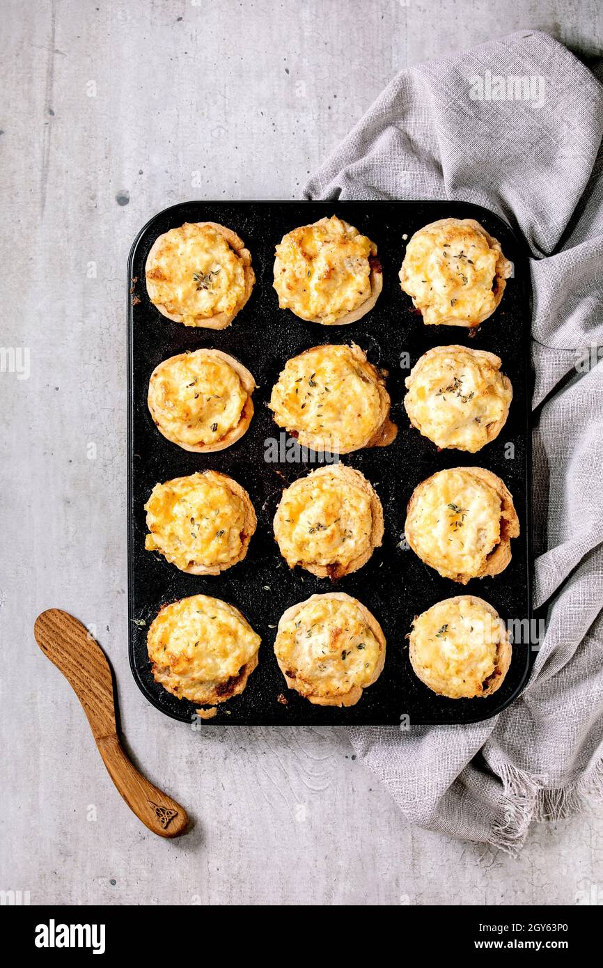 Hausgemachte Mince-Fleisch-Mürbeteig-Mini-Pasteten mit Kartoffelpüree und Thymian in schwarzem Backblech. Graues Leinentuch, grauer Texturhintergrund, flaches Lay Stockfoto