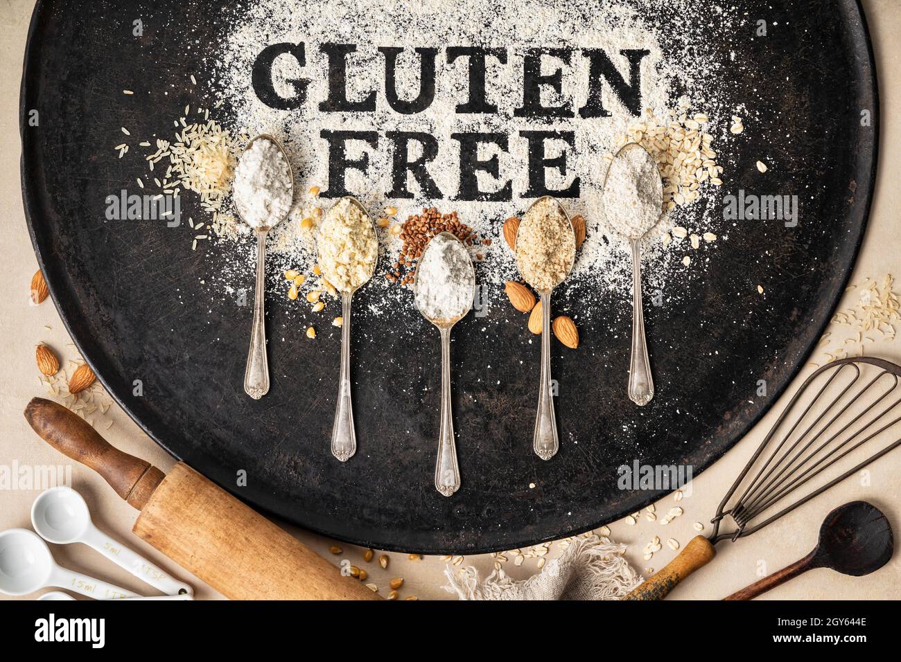 Glutenfrei in Mehl auf Backblech, Küchengeräte und Löffel aus verschiedenen glutenfreien Mehl (Mandelmehl, Buchweizenmehl, Reisfl Stockfoto