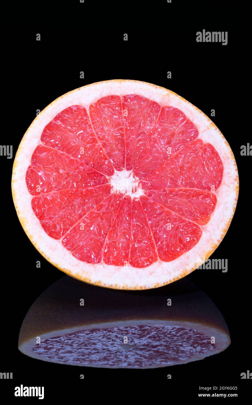 Die Hälfte der Zitrusfrüchte der roten Grapefruit auf schwarzem Hintergrund isoliert; Nahaufnahme Stockfoto