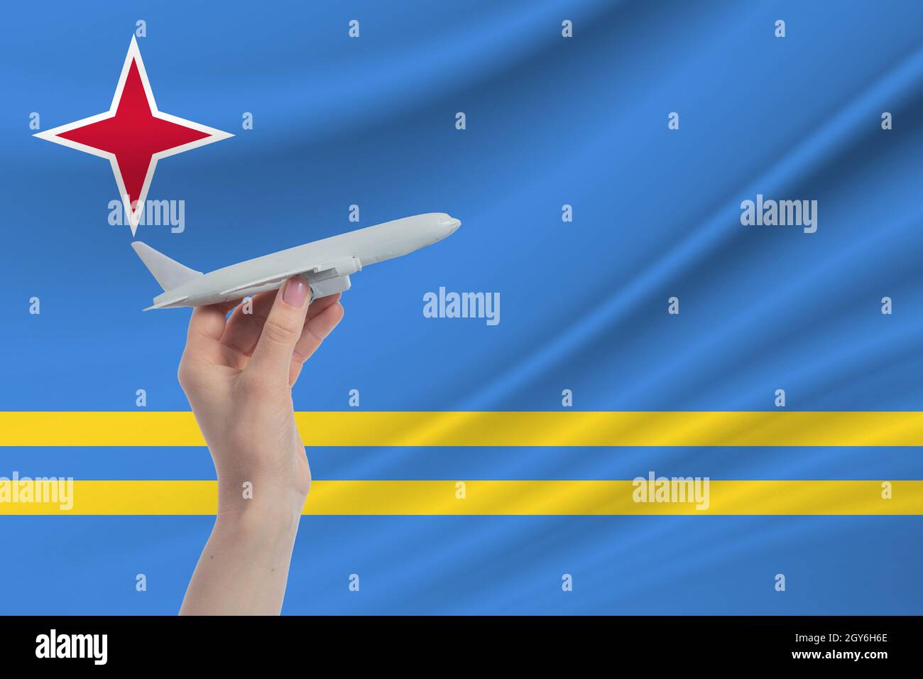 Flugzeug in der Hand mit der Nationalflagge von Aruba. Reisen Sie nach Aruba. Stockfoto
