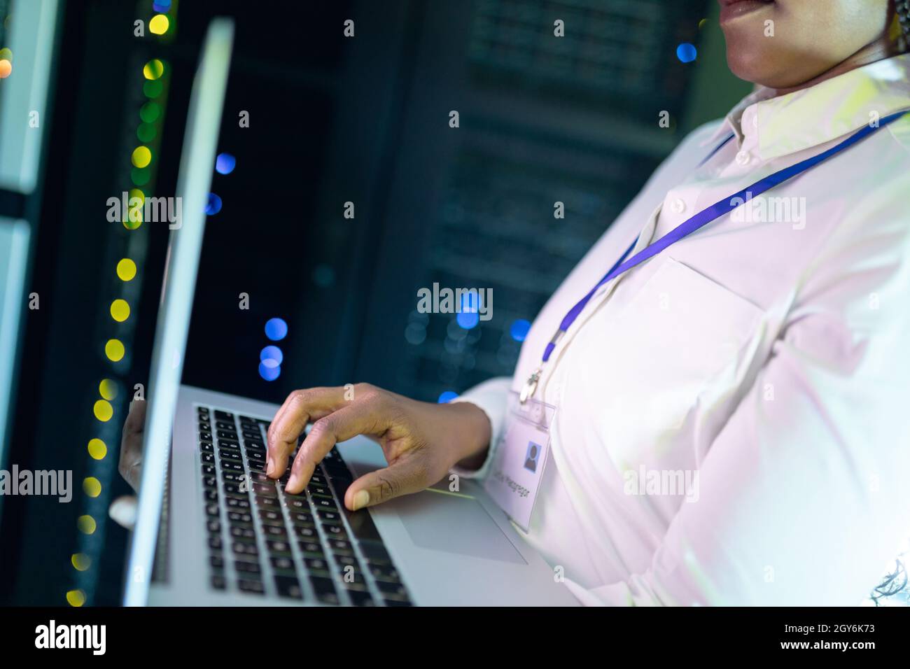 Nahaufnahme einer afroamerikanischen Computertechnikerin, die einen Laptop im Serverraum verwendet Stockfoto
