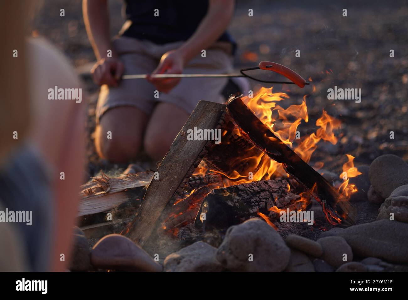 Person, die Hot Dogs über Feuer mit einem Metallrösterstab röstet Stockfoto