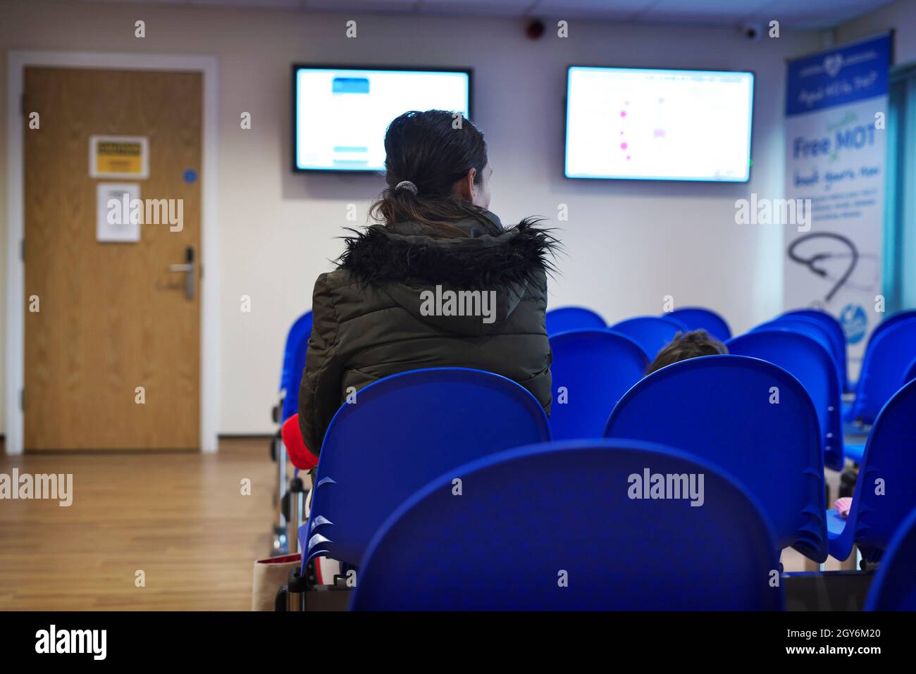 Eine Patientin mit gemischter Rasse, die während einer Pandemie in einem Warteraum für eine GP-Operation sitzt Stockfoto