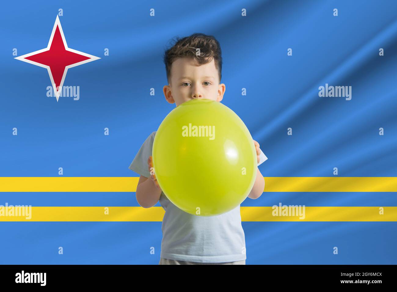 Kindertag auf Aruba. Weißer Junge mit einem Ballon auf dem Hintergrund der Flagge von Aruba. Kindertagesfeier Konzept. Stockfoto