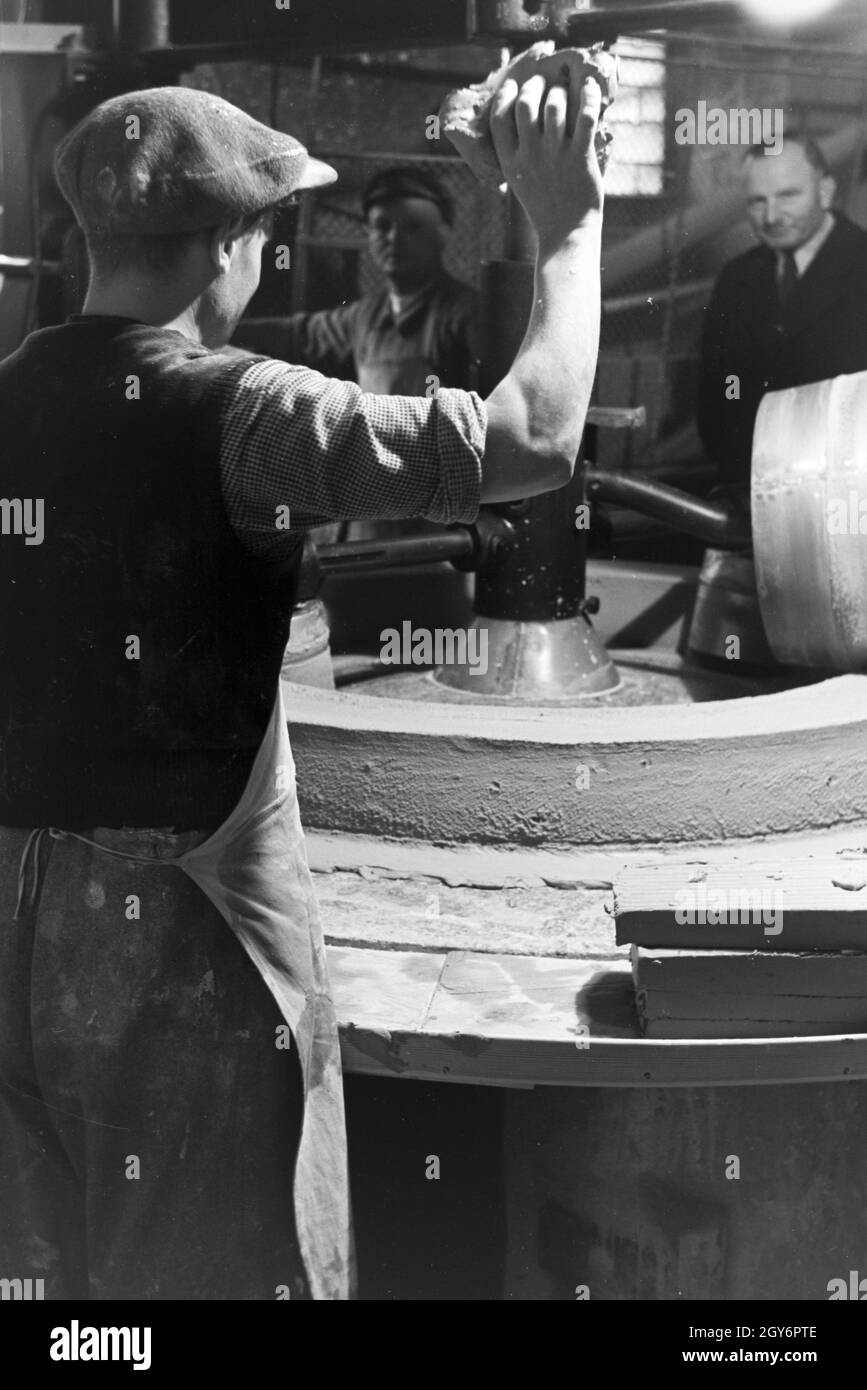 Keramiker der Staatlichen Porzellanmanufaktur Berlin stellen mit Knetmaschine Tonne aus den Rohmaterialien zusammen, Deutschland 1930er Jahre. Keramiker der Staatlichen Porzellanmanufaktur Berlin Ton produziert mit einem Ton Knetmaschine, Deutschland 1930. Stockfoto