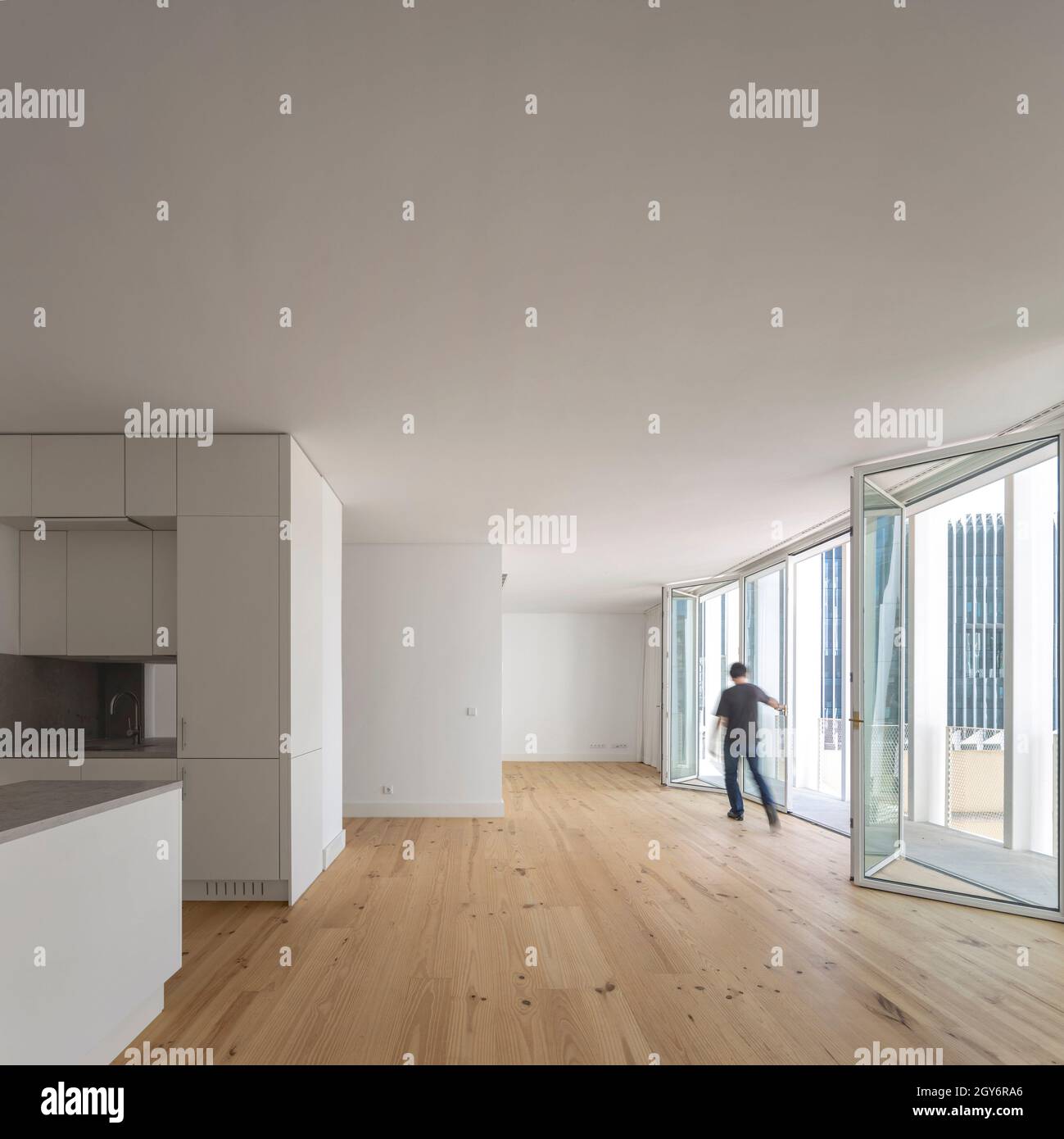 Küche und unmöbliertes Zimmer mit Konzerttüren. Ribeira 11, Lissabon, Portugal. Architekt: Ricardo Carvalho Arquitectos & Associados, 2019. Stockfoto