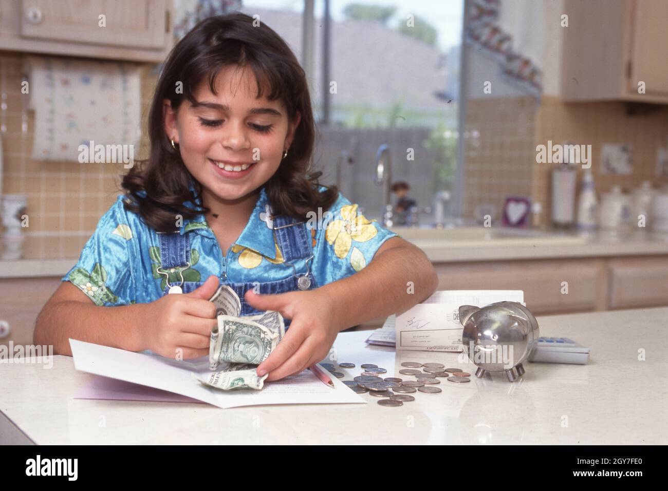 Austin-Texas USA, Juni 1998: Die 8-jährige Panamanisch-Amerikanerin zählt Geld von ihrer Sparkasse, während sie eine Einzahlung auf ihr Bankkonto vorbereitet. ©Bob Daemmrich Stockfoto