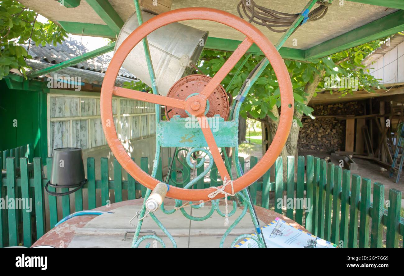 Ein alter Wasserbrunnen mit einem Eimer im Garten, ein Metallgriff zum Abheben des Wassers vom Boden. Dorf weit unter dem Dach mit einem Seil. Retro Well i Stockfoto