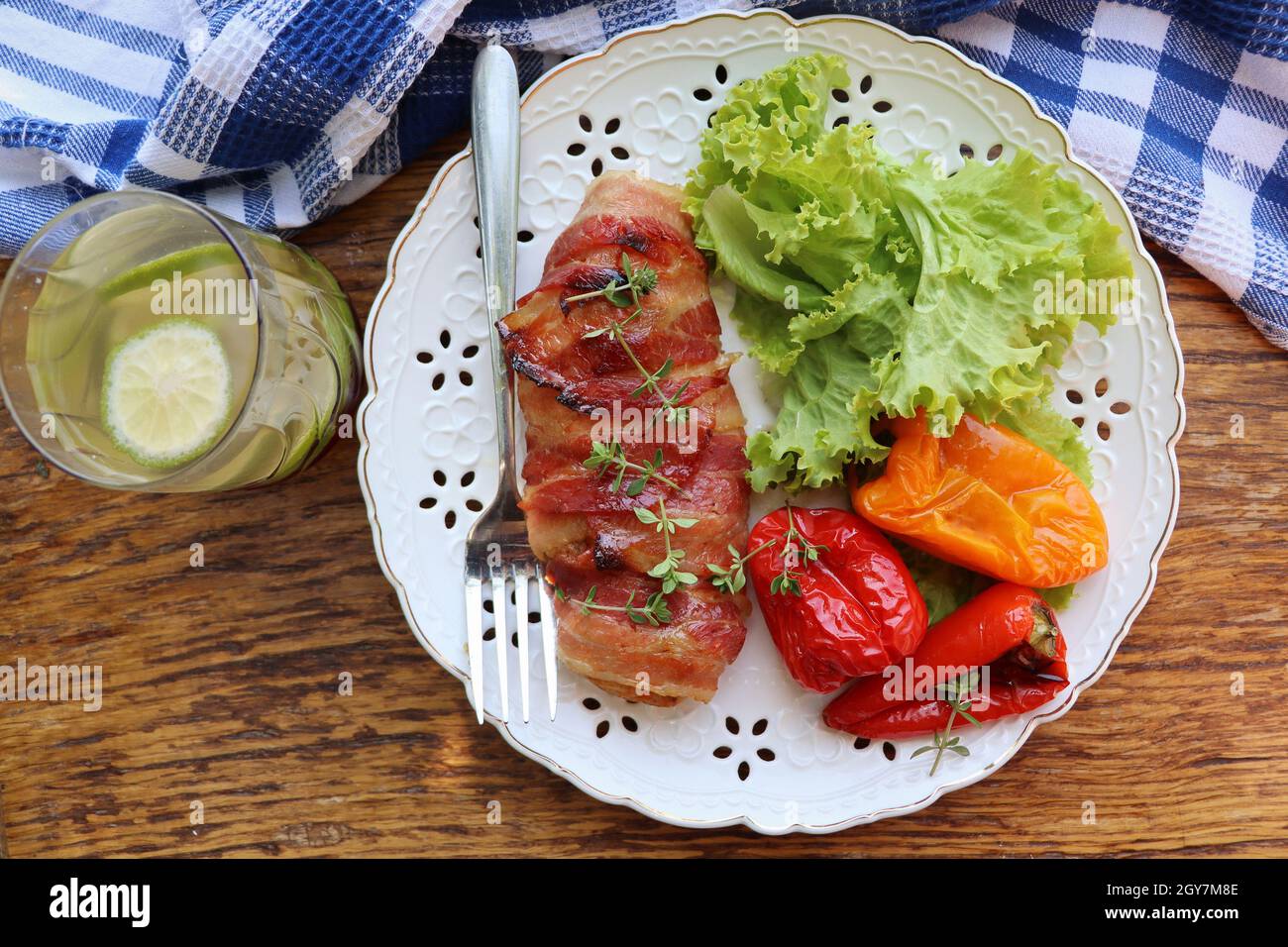 Abendessen im Hintergrund. Gegrillte Hähnchenbrust in Speck verpackt serviert mit Salat auf Holz rustikalen Tisch. Draufsicht . Stockfoto