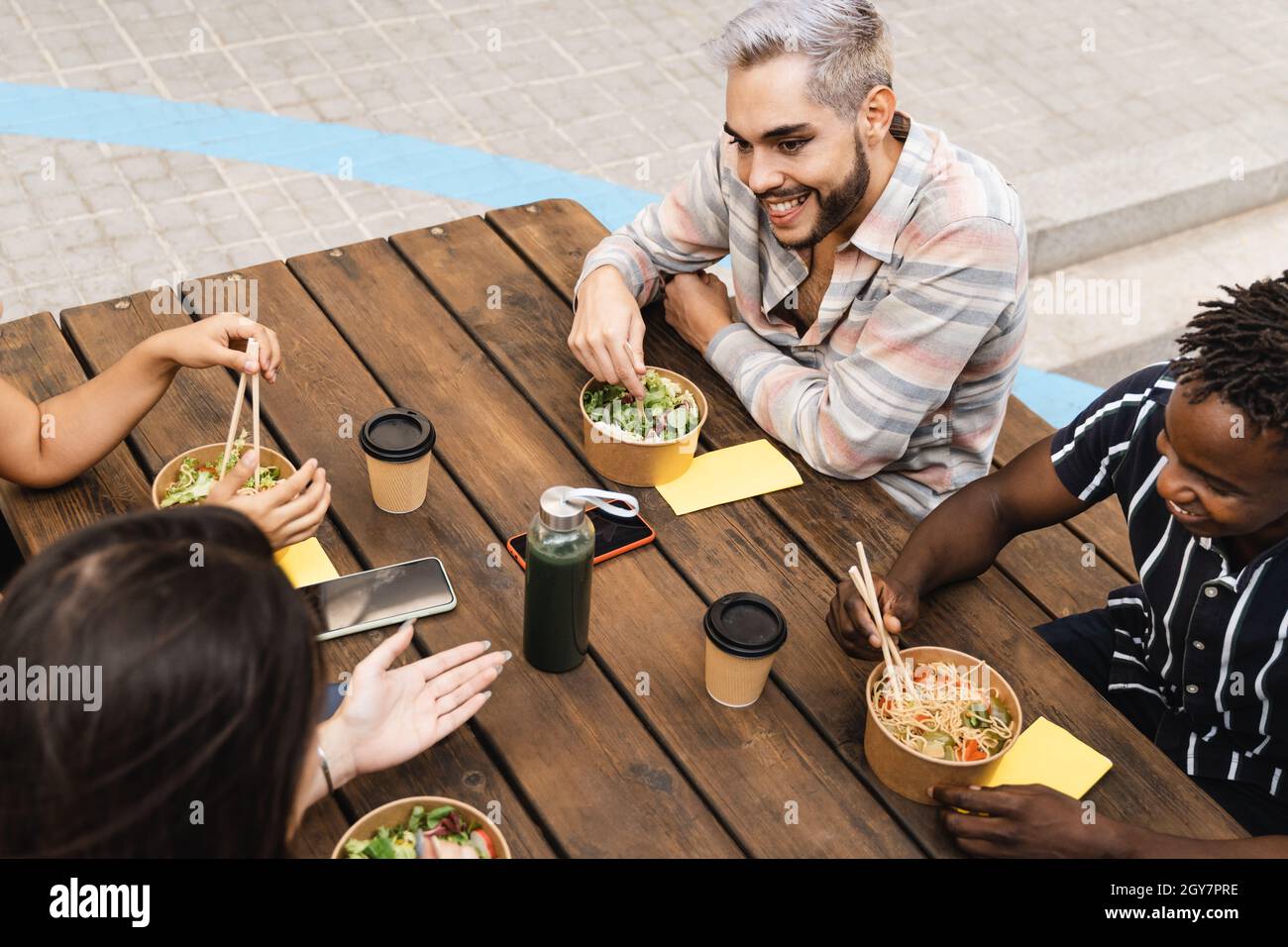 Diverse Freunde essen Essen zum Mitnehmen im Freien - echte Menschen, Millennial Lifestyle - Fokus auf queer Mann Stockfoto