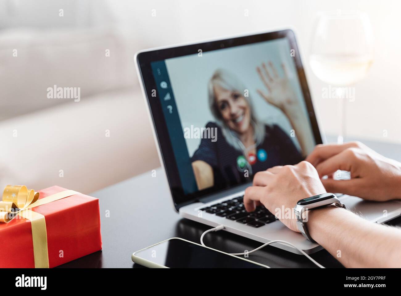 Generationsübergreifende Familie feiert Weihnachten mit Videoanruf - Senior Woman chatten und treffen sich auf einem Laptop - Fokus auf die linke Hand Stockfoto