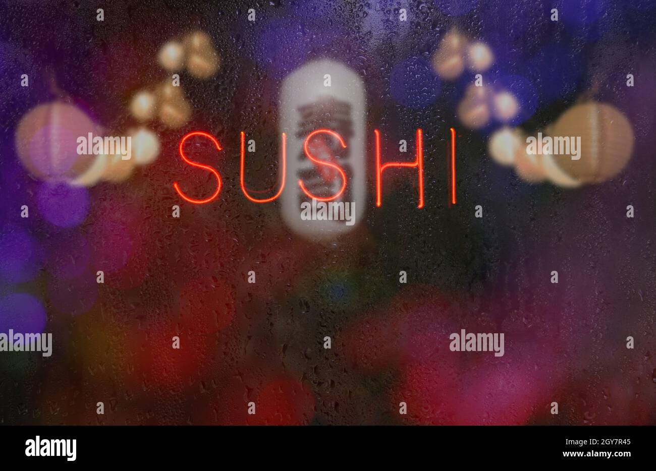 Neon Sushi-Schild im Wet Window mit japanischer Sushi-Laterne im Hintergrund Stockfoto