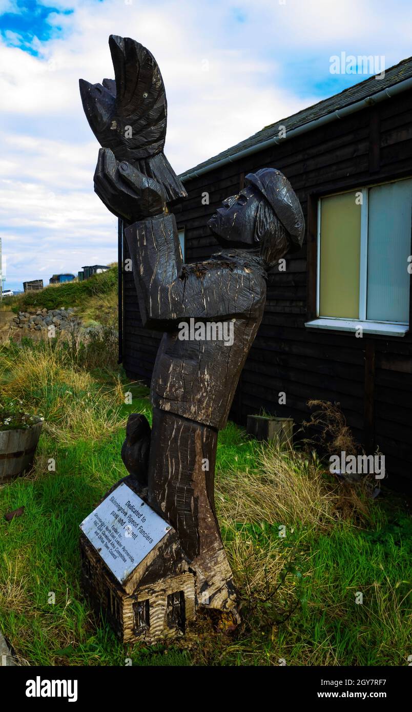 Holzskulptur eines Mannes mit Tauben außerhalb des Club-Hauses der Skinningrove Homing Gesellschaft, einem Verein für Taubenzüchter Stockfoto