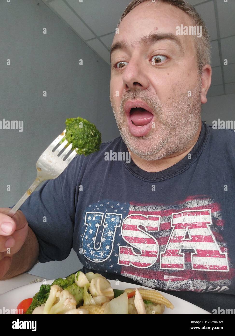 Ein fetter amerikanischer Mann, der Broccoli isst Stockfoto