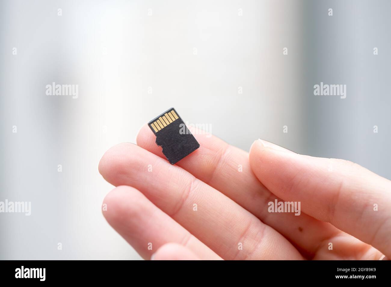 Der junge Mann hält eine kleine Speicherkarte in der Hand, Textraum Stockfoto