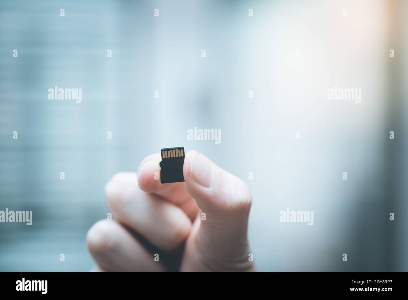 Der junge Mann hält eine kleine Speicherkarte in der Hand, Textraum Stockfoto