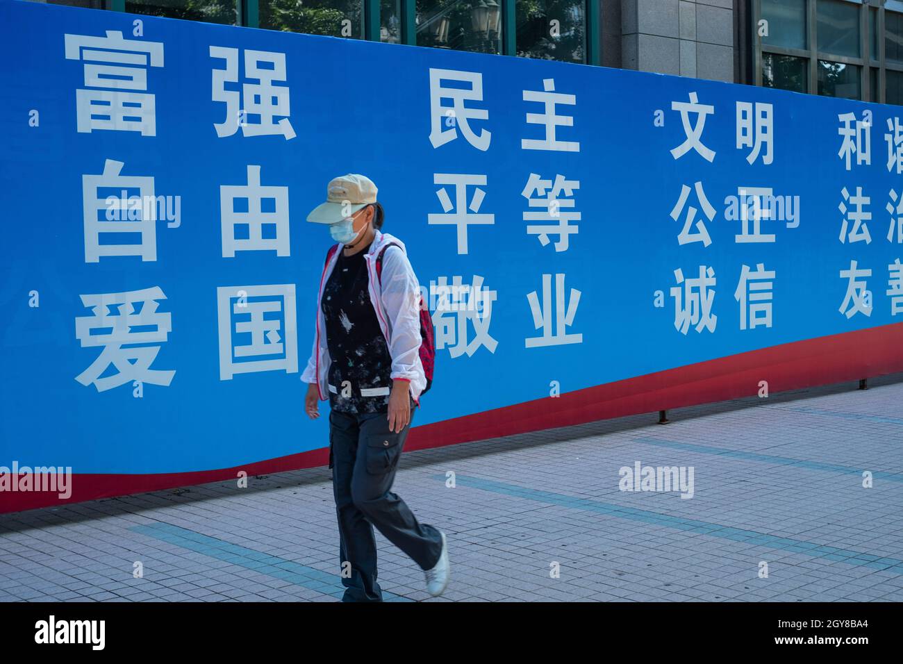 Eine chinesische Dame kommt an einer Plakatwand vorbei, auf der die zentralen sozialistischen Werte Chinas in Peking, China, zu sehen sind. 07-Okt-2021 Stockfoto
