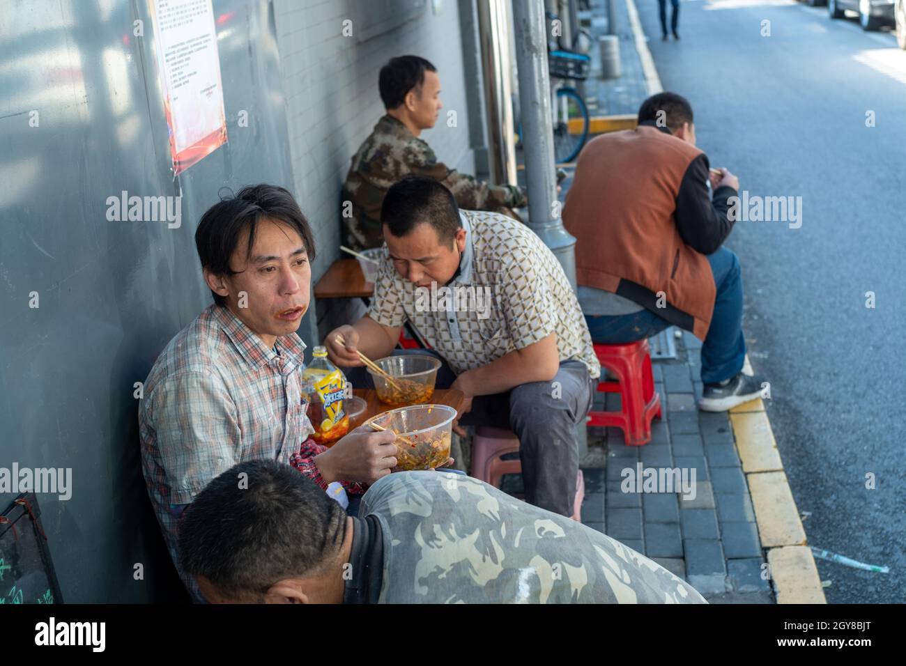 Chinesische Bauarbeiter essen in einer Gasse in Peking, China, zu Mittag. 07-Okt-2021 Stockfoto