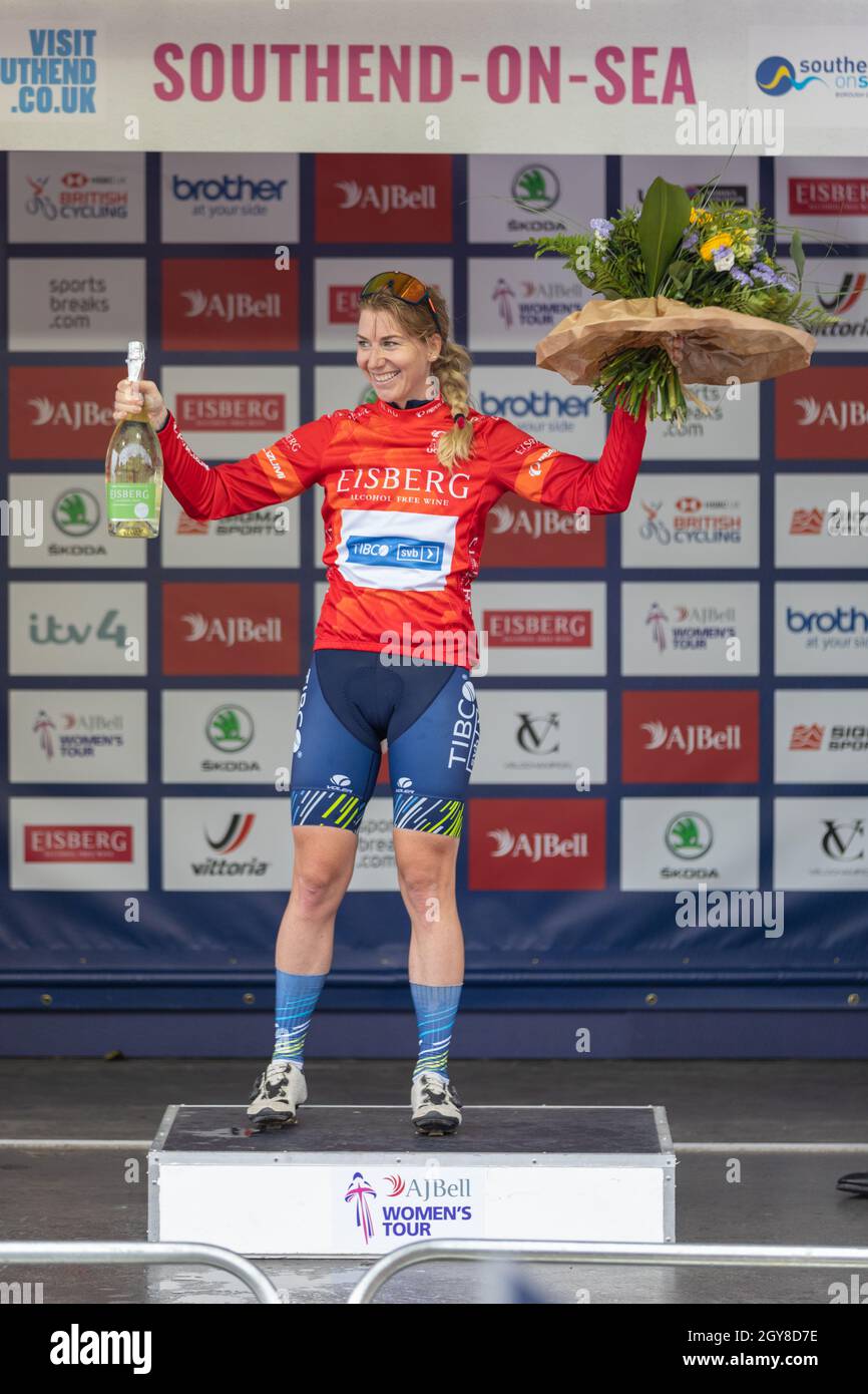 Southend on Sea, Großbritannien. Oktober 2021. Nina Kessler, Eisberg Sprints Trikotführerin feiert ihren ersten Platz am Ende der AJ Bell Women’s Tour in Southend-on-Sea. Sie trägt ein rotes EISBERG-Trikot und blaue VITUS-Shorts und steht auf dem zentralen Podium mit einem Blumenstrauß und einer Flasche Wein oder Champagner. Sponsorlogos wie Brother, Skoda, AJ Bell, Vittoria und Southend-on-Sea sind im Hintergrund zu sehen. Penelope Barritt/Alamy Live News Stockfoto