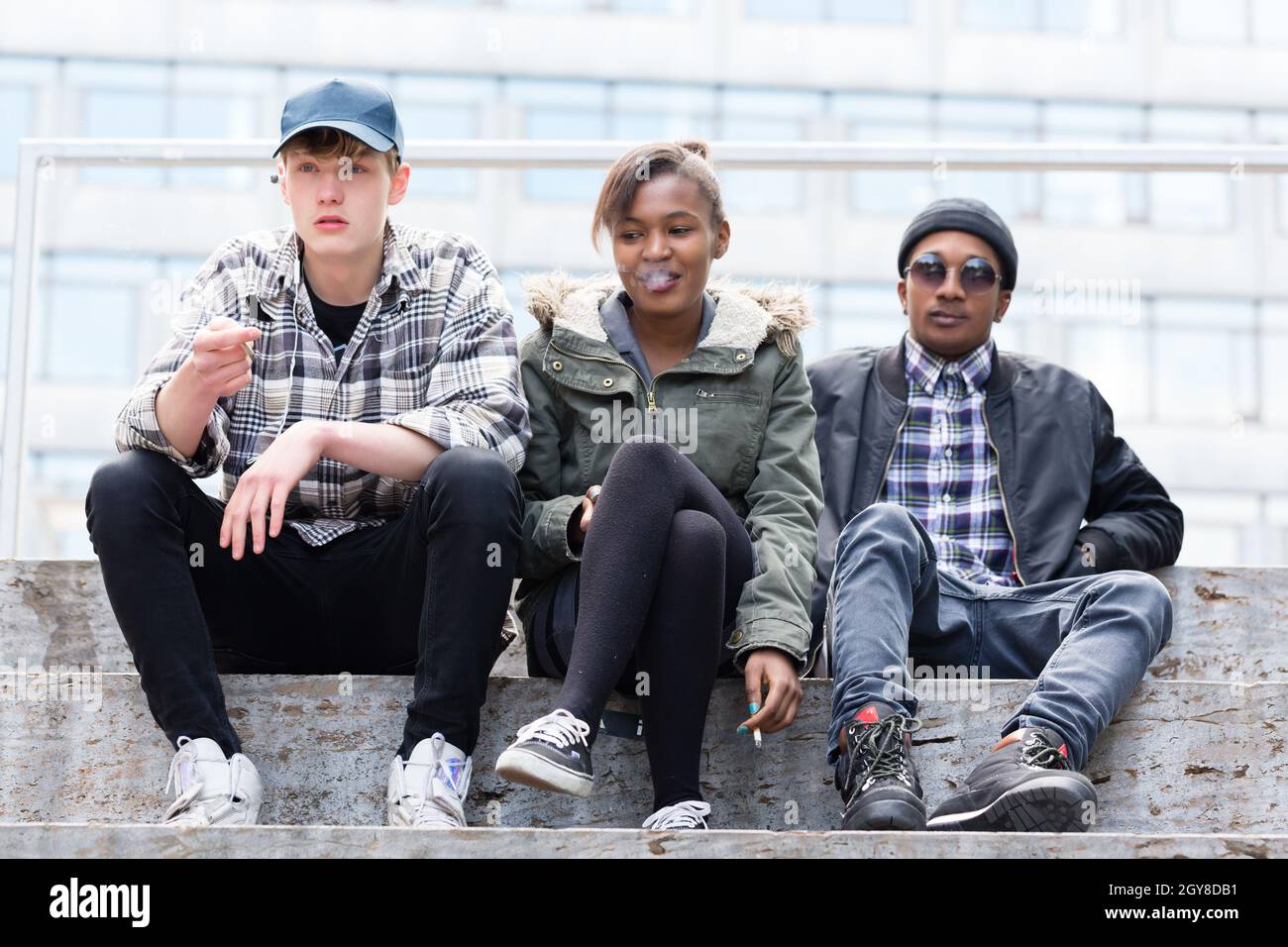 Eine Gruppe von Freunden sitzt auf der Treppe und genießt das Rauchen Stockfoto