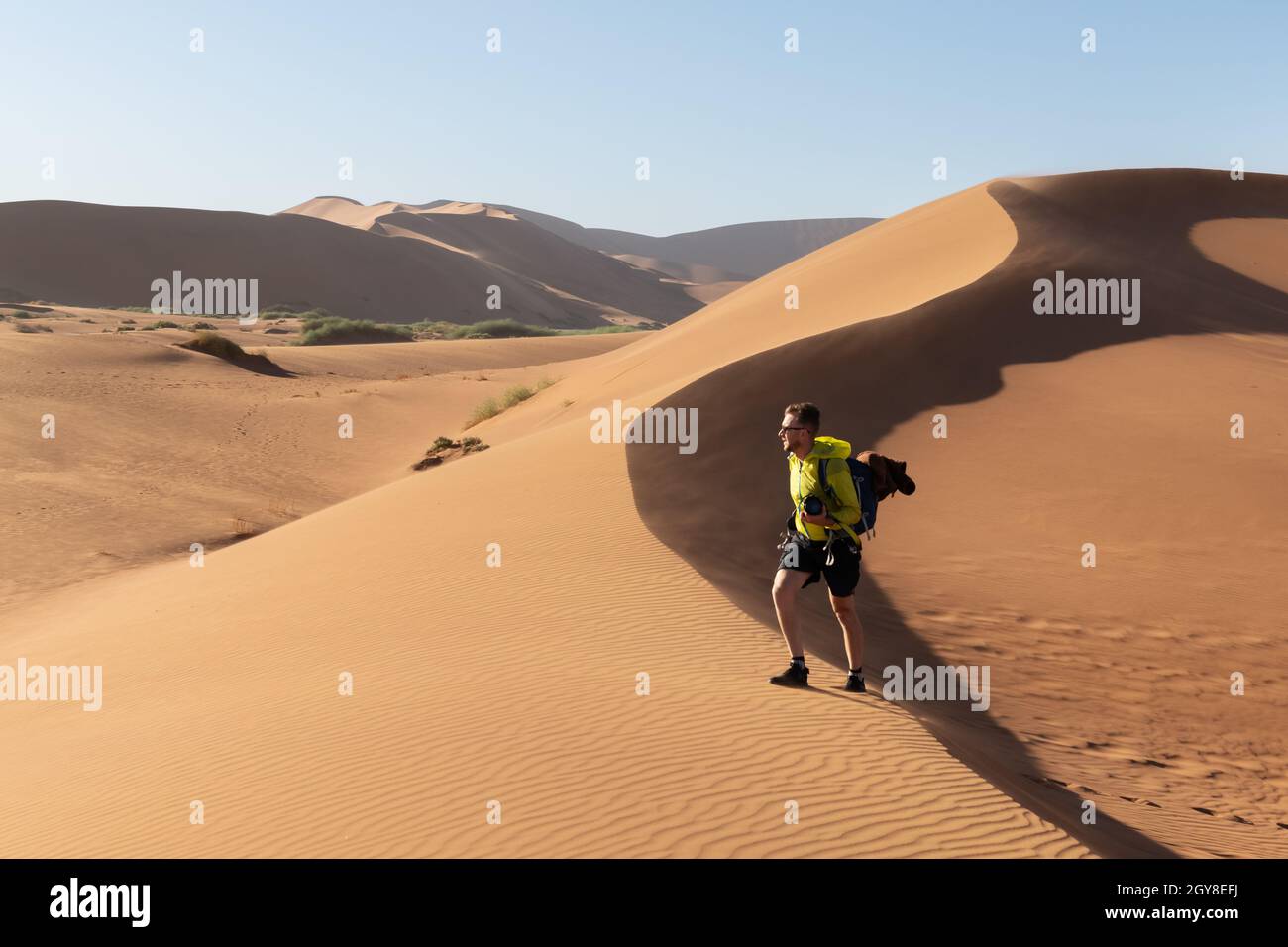 Fotograf, der in Deadvlei, Namib-Naukluft Nationalpark, Namibia, Afrika fotografiert. Getrockneter Boden mit Sand in der Namib Wüste bei Sonnenuntergang. Landschaftsfotografie Stockfoto