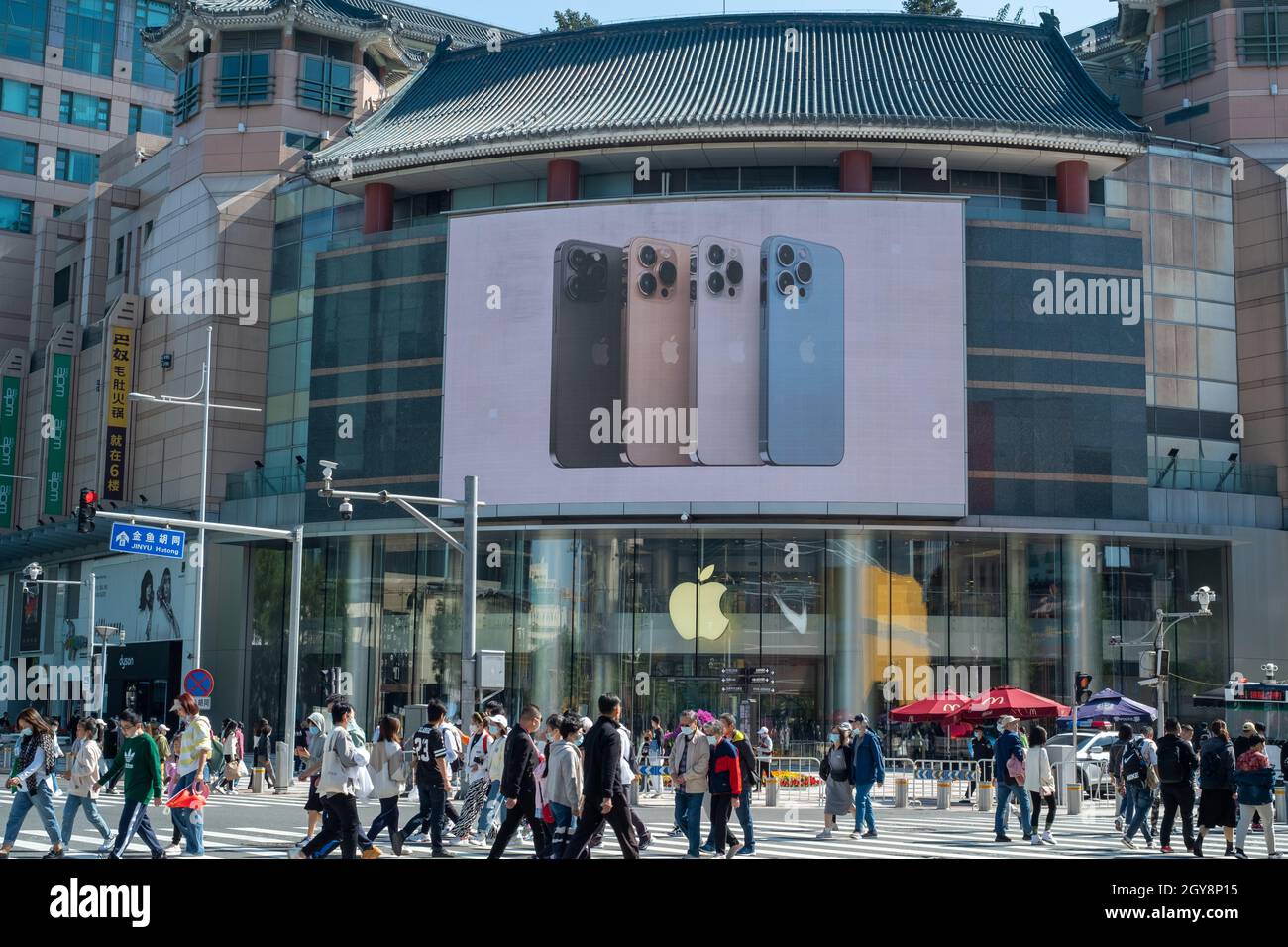 In Peking, China, laufen die Menschen an einem Apfelladen in Wangfujing vorbei, in dem die Werbung der iPhone 13-Serie auf einem großen Bildschirm erscheint. 07-Okt-2021 Stockfoto