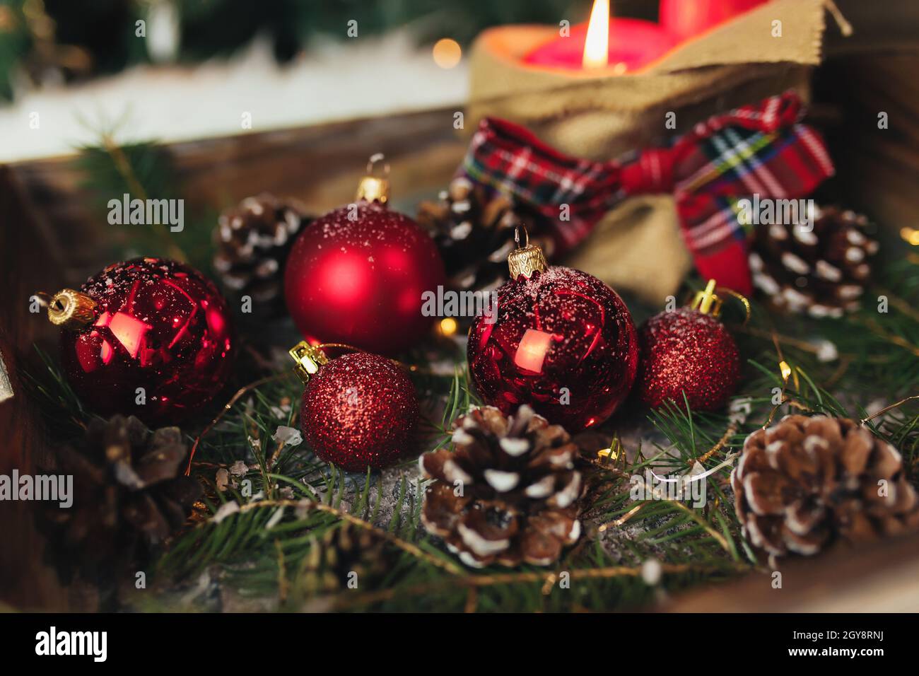 Rote weihnachtsdekorationen auf dem Tisch bei verschwommenem weihnachtsbaum mit Kerzen. Hochwertige Fotos Stockfoto