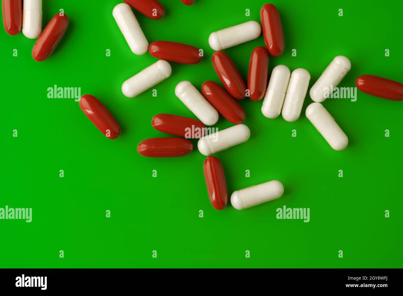 Weiße und rote Pillen auf grünem Hintergrund Stockfoto