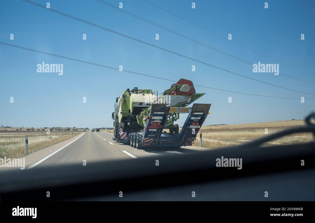 Fahren hinter einem schweren LKW mit Harvester. Schwerlasttransporte. Blick von innen Stockfoto