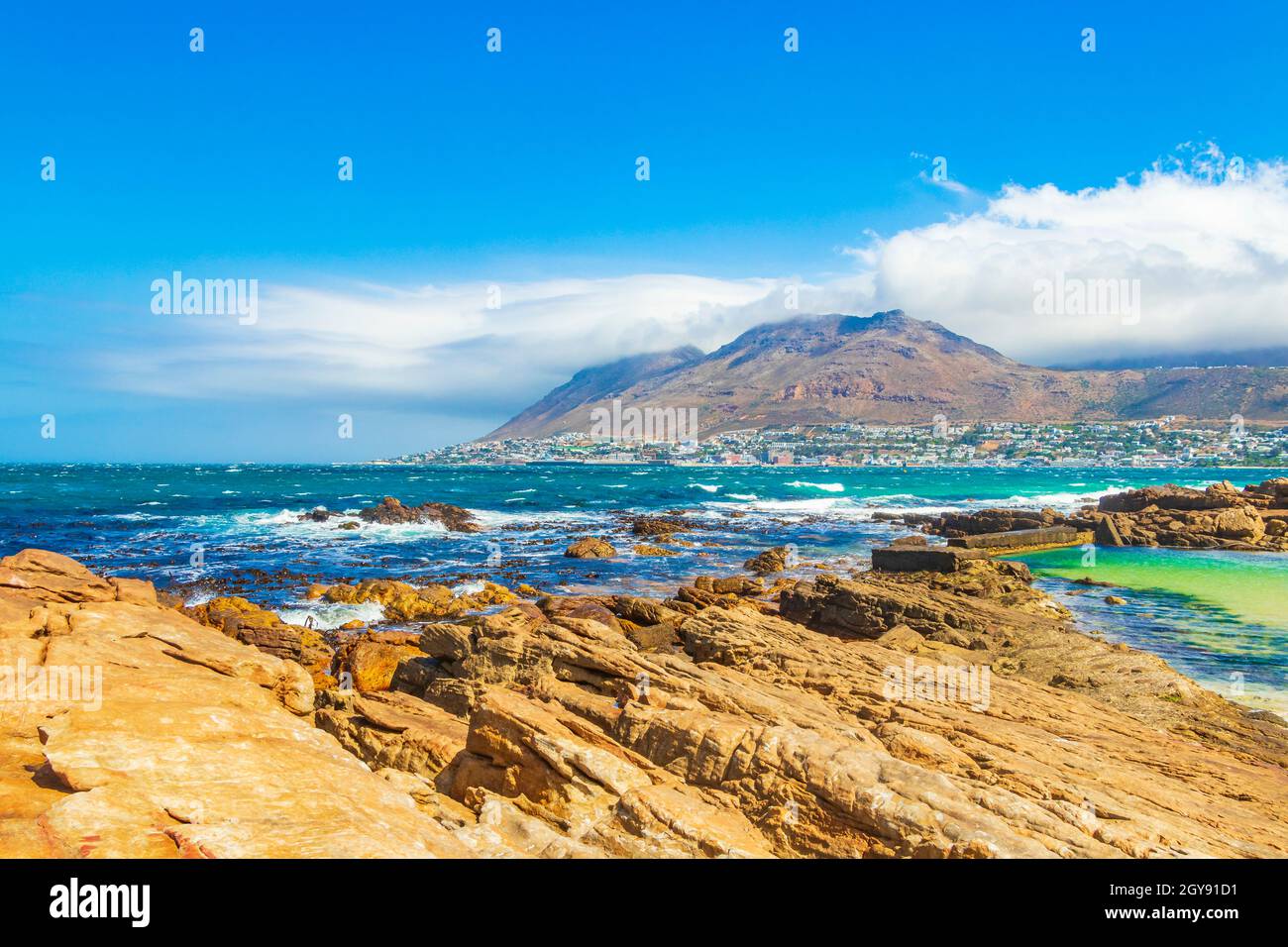 False Bay raue Küstenlandschaft mit Felsbrocken Wellen und Berge mit Wolken in Glencairn Simons Town Kapstadt Westkap Südafrika. Stockfoto