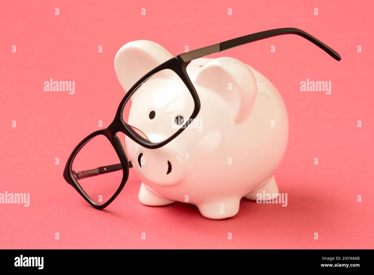 Sparschwein und Brillen auf dem rosa Hintergrund. Finanzkonzept. Stockfoto