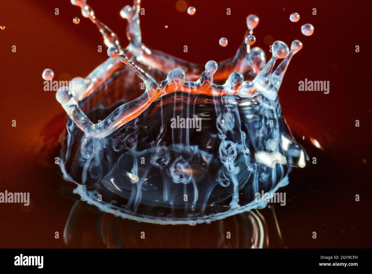 Geisterhaft weißes Wassertropfen mit einem karmesinroten Hintergrund Stockfoto