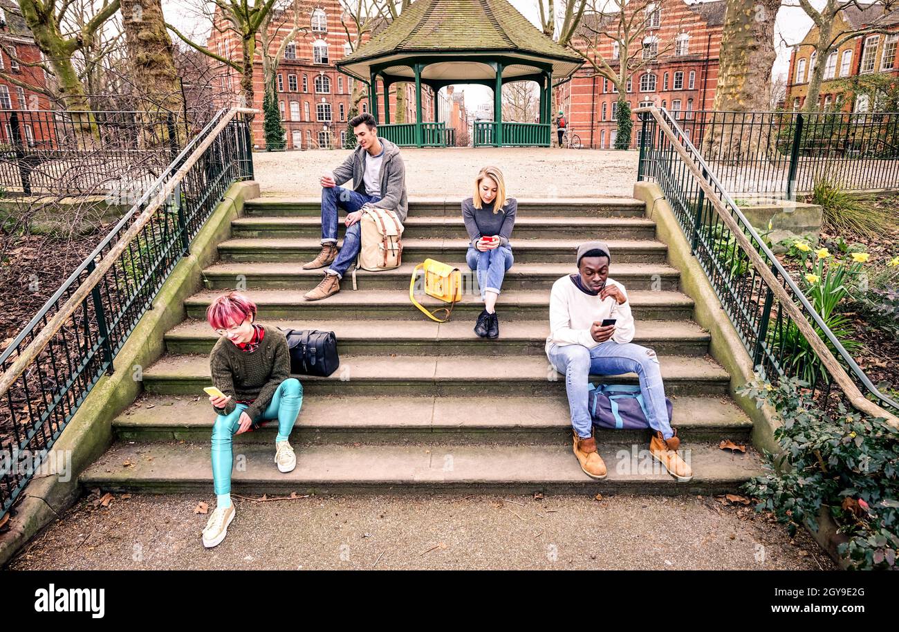 Gruppe von multirassischen Freunden mit Handy sitzen auf der Treppe im Park - Junge Hipster Menschen süchtig nach Smartphone in sozialen Netzwerken Stockfoto
