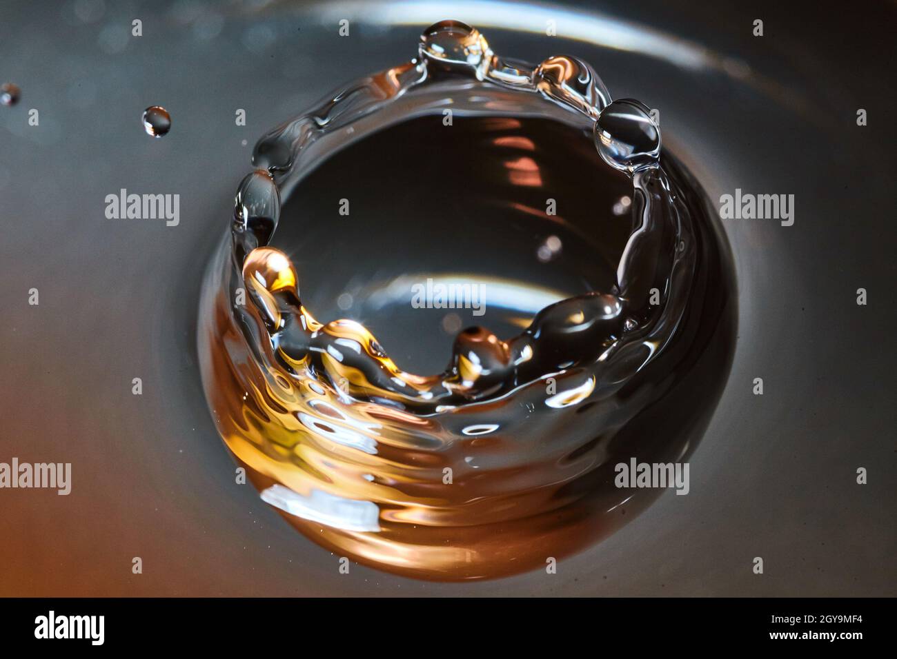 Krone aus Wasser mit einem Wassertropfen, der schwarz, Gold und weiß ist Stockfoto