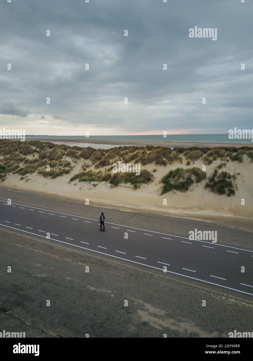 Isolierter Mann, der ein Skateboard in abgelegener Lage am Strand reitet Stockfoto
