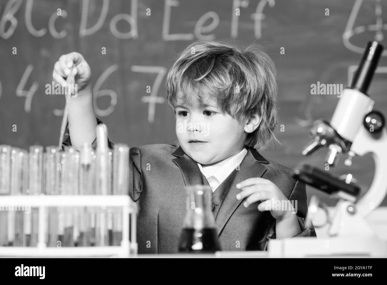 Kind studieren Chemie Schulstunde. Schulbildung. Junge verwenden Mikroskop und Reagenzgläser im Schulunterricht. Chemische Analyse. Kleinkind Genie Baby Stockfoto