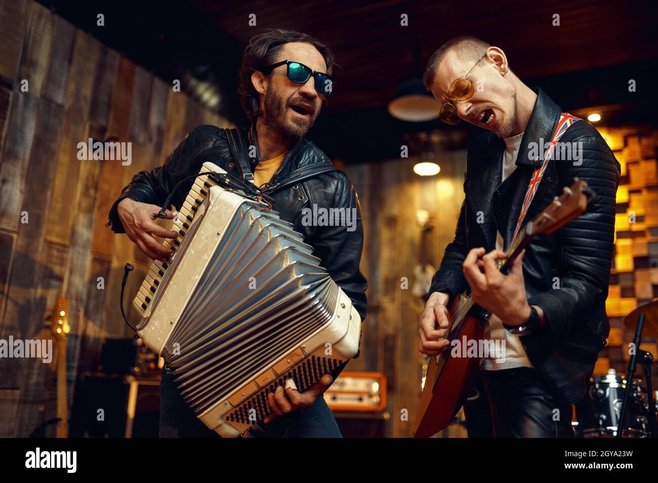 Zwei brutale Künstler mit Akkordeon und Balalaika, Musik auf der Bühne. Rockband Auftritt oder Wiederholung in der Garage, Mann mit Musikinstrument Stockfoto