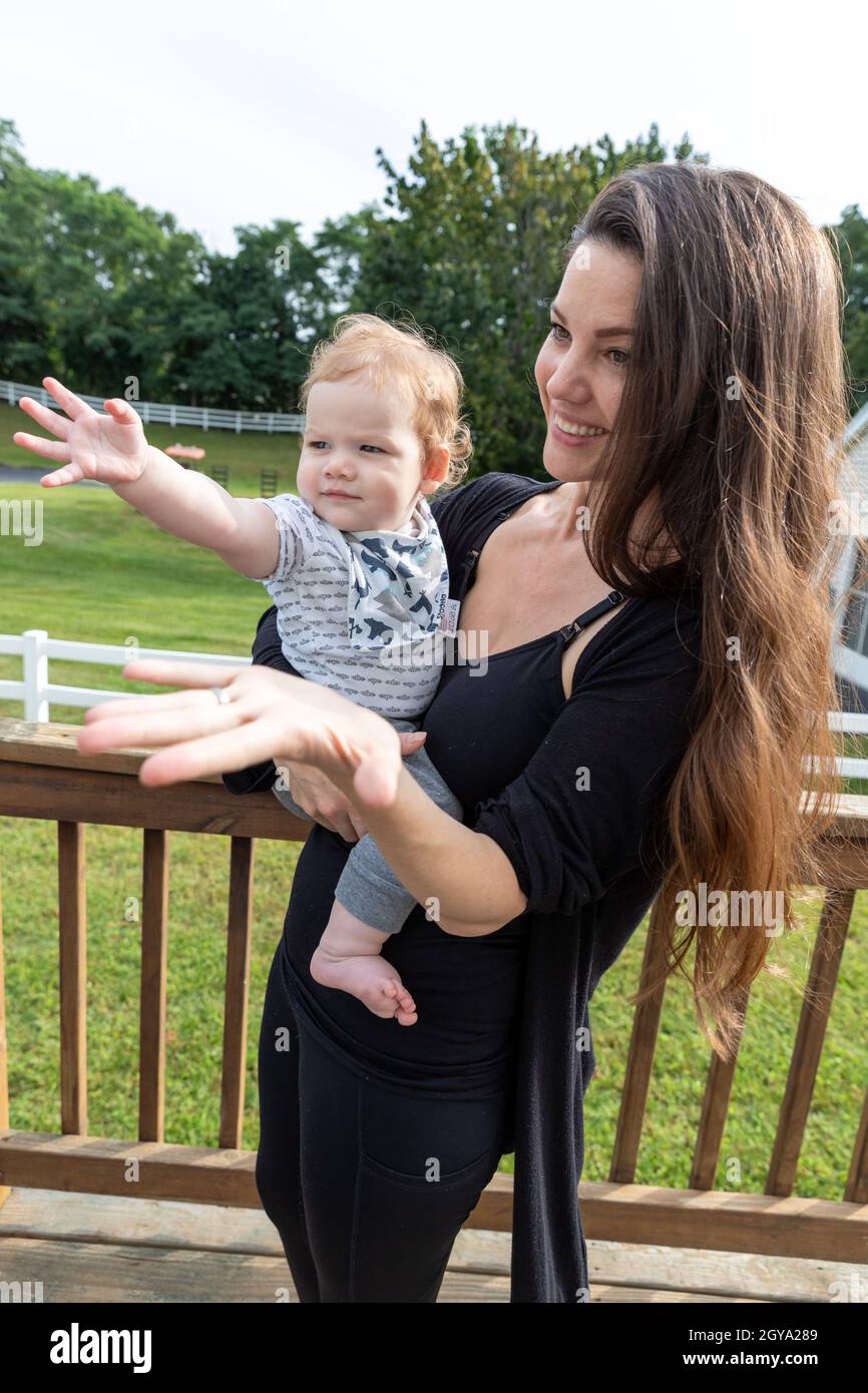Schöne Mutter hält Baby Junge streut seine Hand. Stockfoto