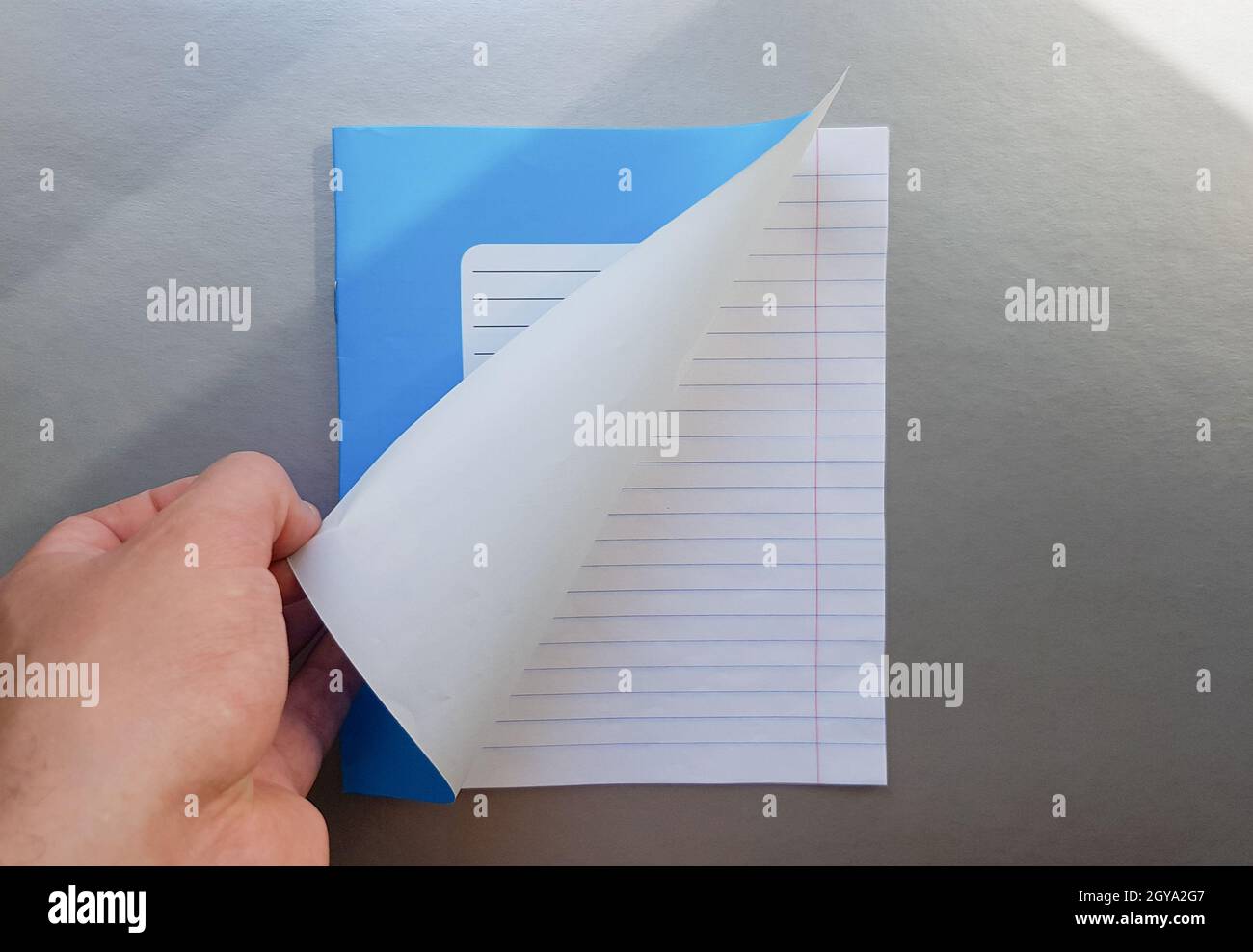 Designkonzept - Draufsicht einer hochwertigen männlichen Hand, die durch ein Blatt blau gestreiftes Notizbuch blättert. Draufsicht, Kopierbereich, flach liegend. Stockfoto