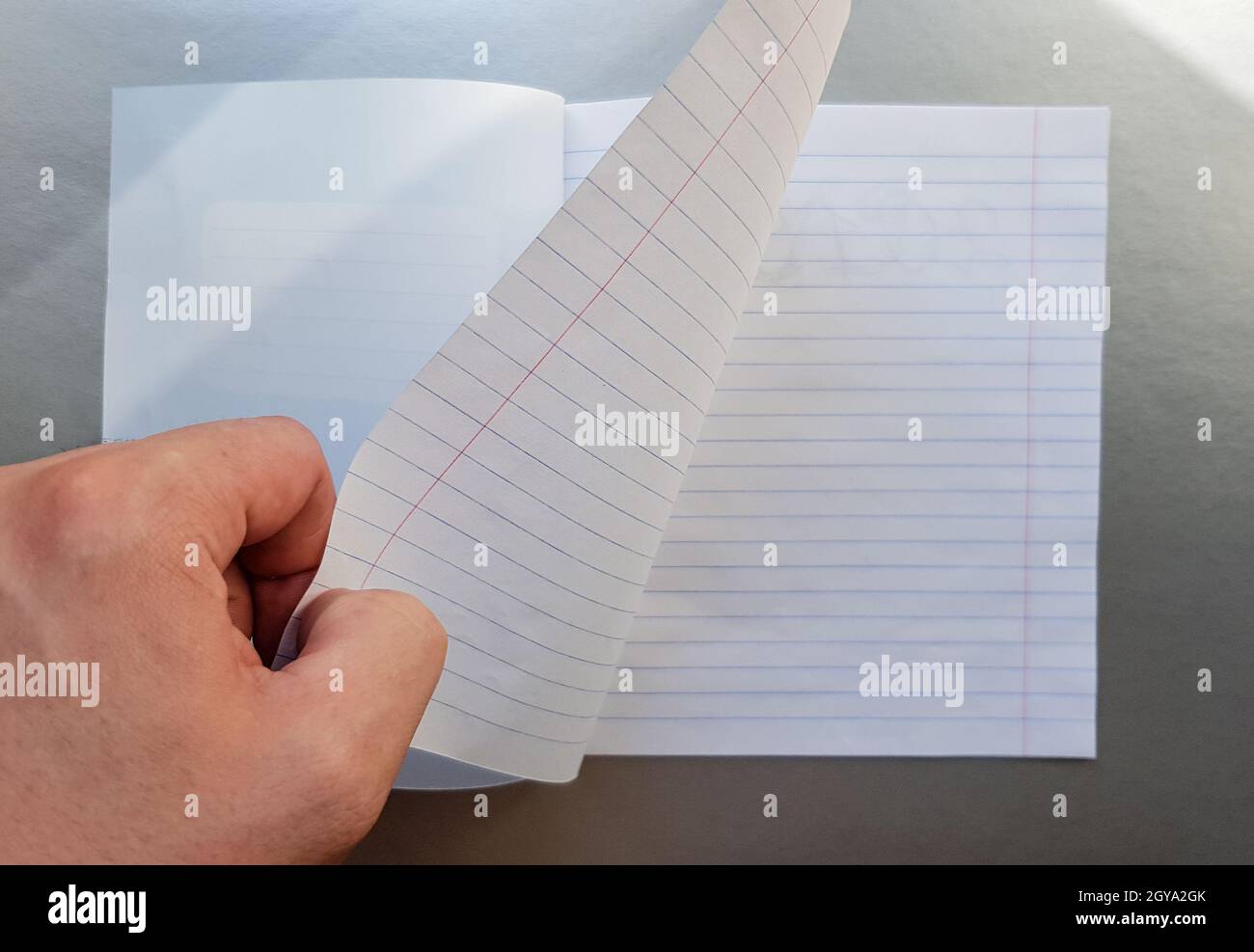 Designkonzept - Draufsicht einer hochwertigen männlichen Hand, die durch ein Blatt blau gestreiftes Notizbuch blättert. Draufsicht, Kopierbereich, flach liegend. Stockfoto