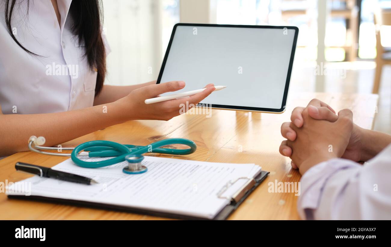 Arzt, der ein Tablet-PC verwendet, diskutierte etwas mit dem Patienten. Stockfoto