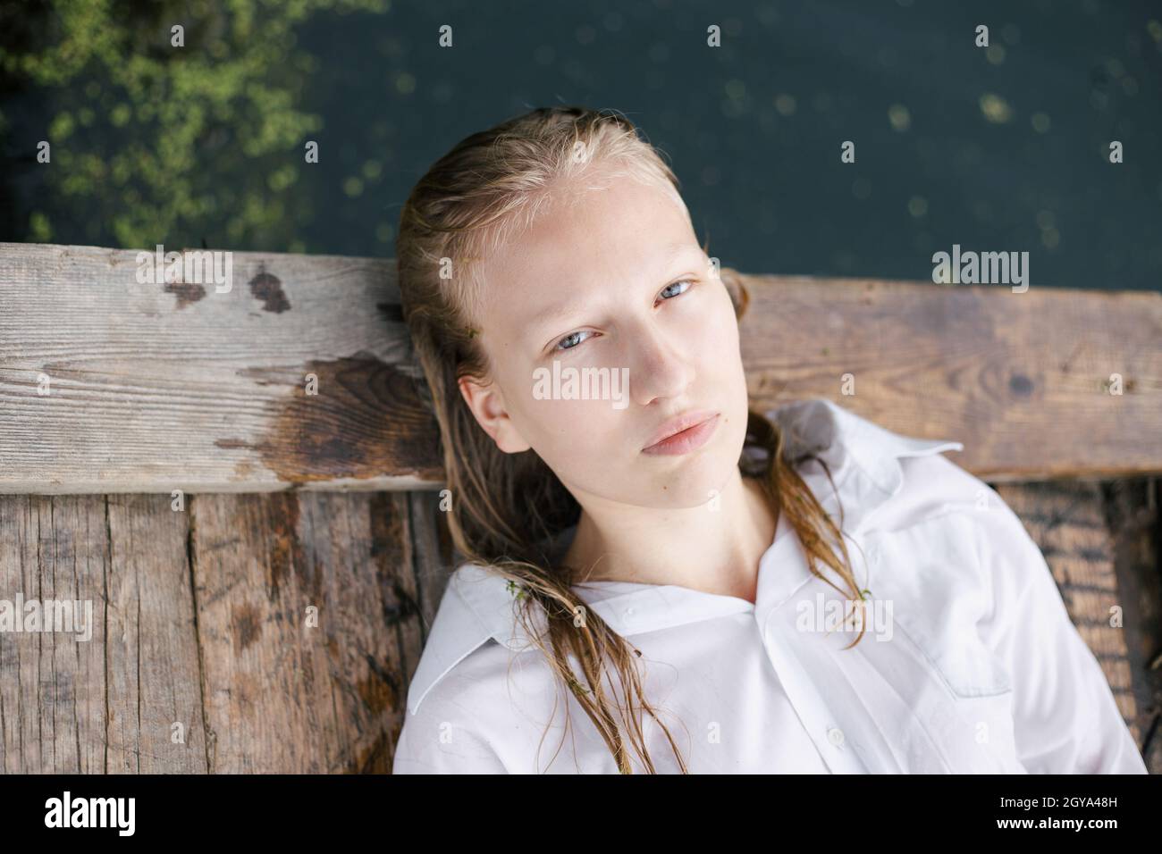 Junges Mädchen mit nassem Haar liegt am Wasser auf Holzfloß Stockfoto