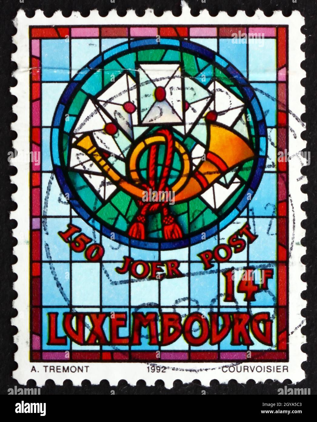 LUXEMBURG - UM 1992: Eine in Luxemburg gedruckte Briefmarke zeigt Post Horn und Briefe, Glasfenster von Auguste Tremont, um 1992 Stockfoto