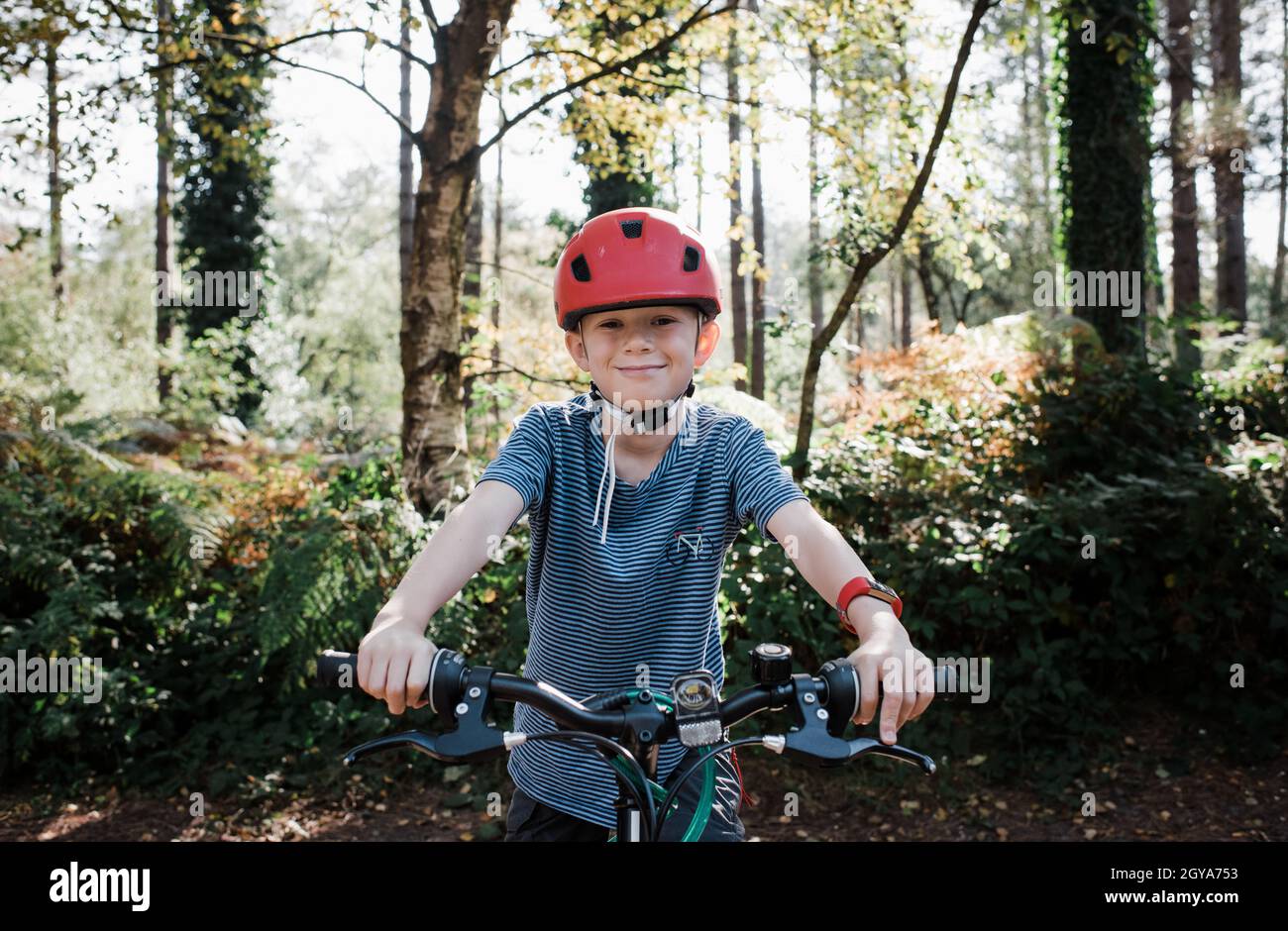Porträt eines lächelnden Jungen saß auf seinem Fahrrad im Wald Stockfoto