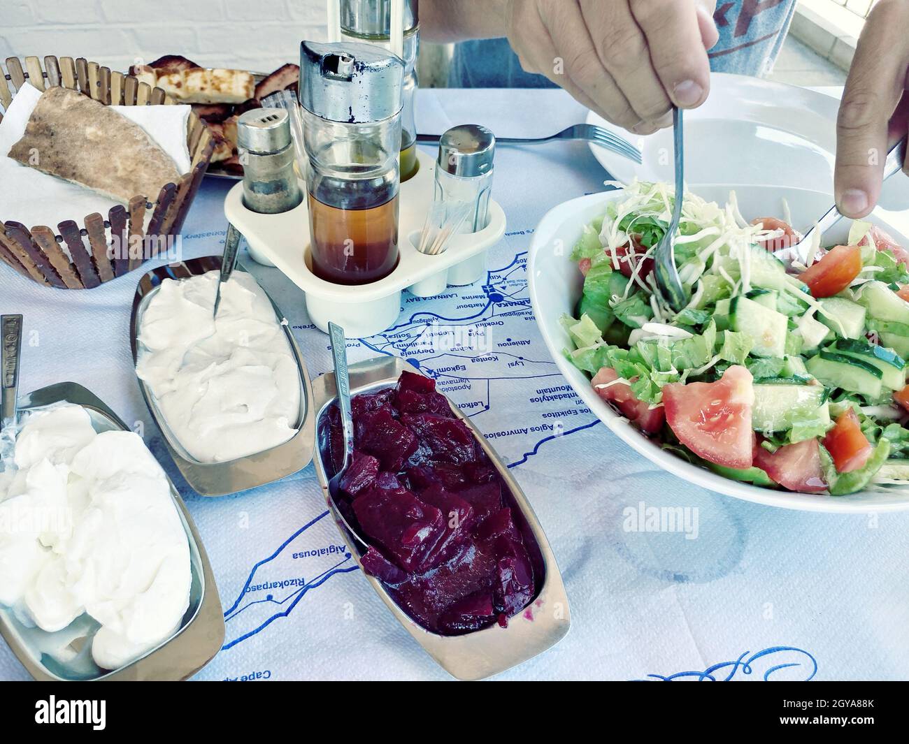 Griechisches Frühstück, rustikaler Stil. Gemüsesalat, verschiedene Beläge, gebratene Halloumi und gebratenes Schweinefleisch Stockfoto