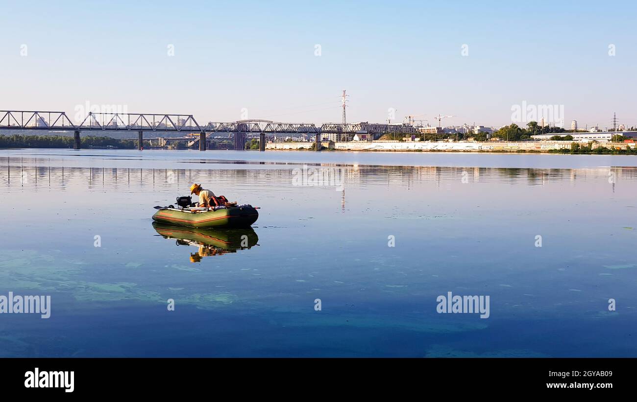 Ukraine, Kiew - 20. August 2019: Angeln. Fischer auf einem aufblasbaren Boot mit Angelausrüstung auf einem Fluss in der Stadtgrenze an einem sonnigen Sommermorgen Stockfoto