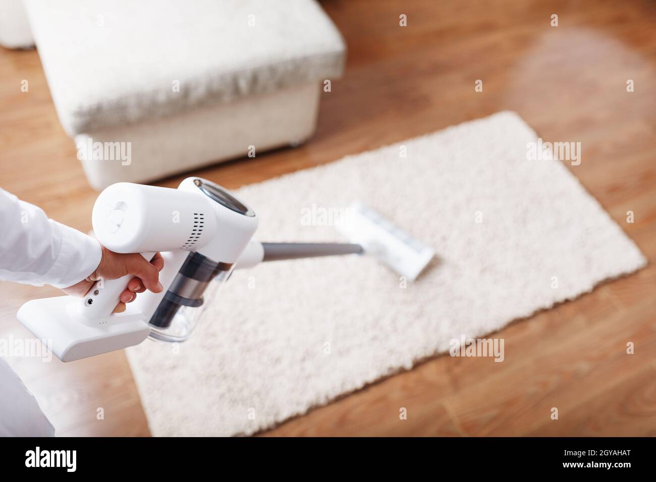 Die Turbo-Bürste eines kabellosen Staubsaugers reinigt den Teppich im Haus in Nahaufnahme. Moderne Technologien für die Reinigung. Stockfoto